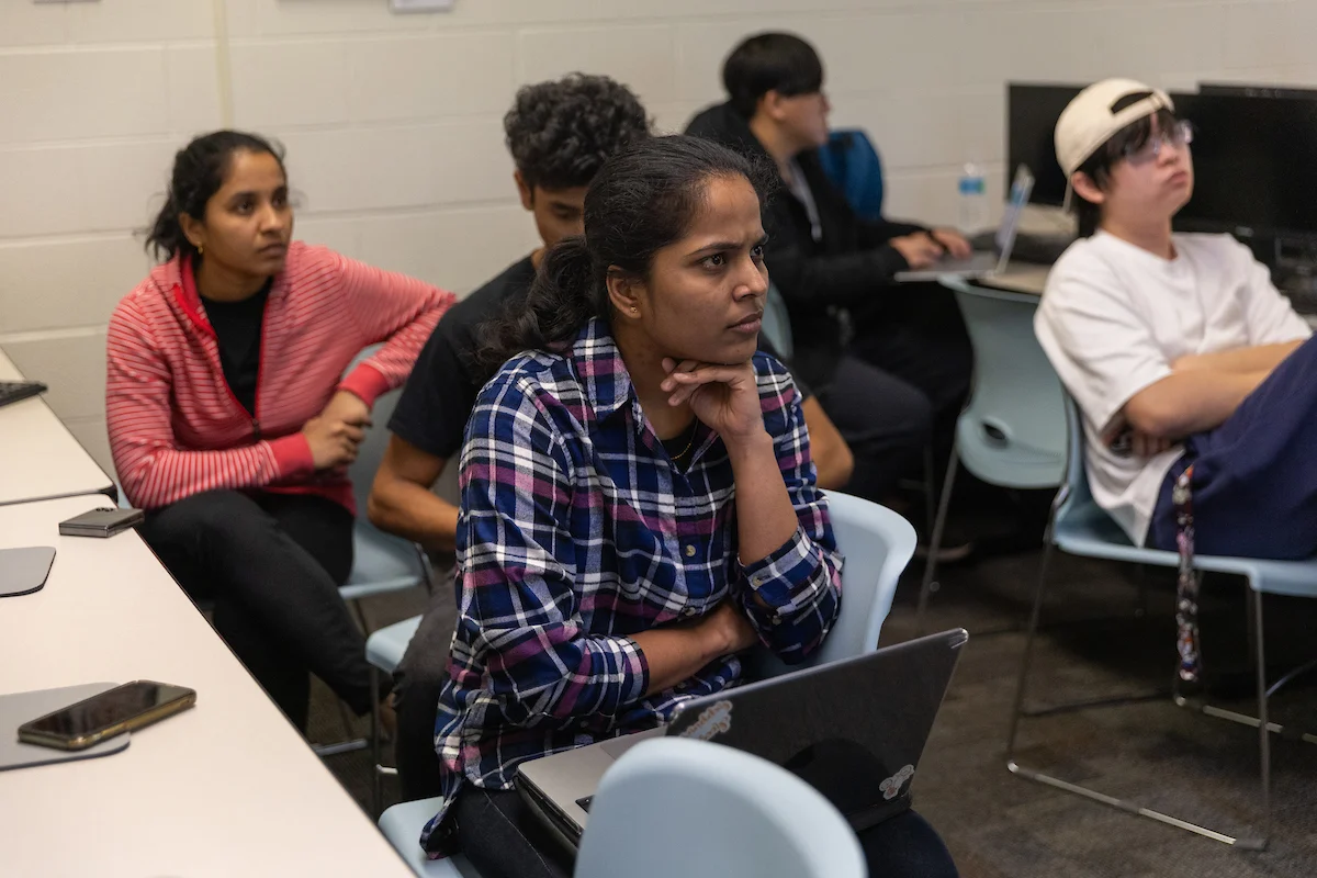 Students sit in a classroom, attentively listening, with laptops and notebooks on their desks, ready to learn and contribute to Uplift Valpo.