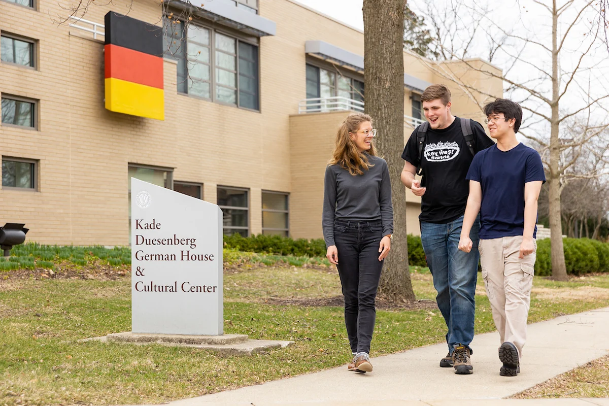 Three students, pursuing a German Minor, walk and talk outside the Kade Duesenberg German House & Cultural Center.