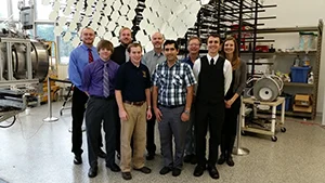 Nine members of the Solar Team pose together in a laboratory, with scientific equipment in the background.