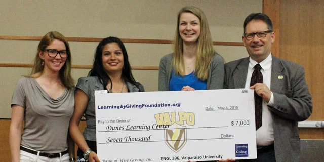 Four people smiling and holding a large $7,000 check for Dunes Learning Center from Valparaiso University, highlighting philanthropy in practice.