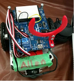 A small robotics research robot with wires, a claw arm, and a green label reading "Allen" on its front.