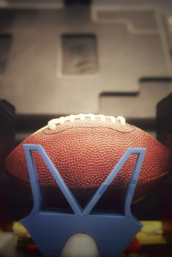 A close-up of an American football resting on a blue kicking tee, with a blurred background—perfect for showcasing Valpo Robotics team spirit.