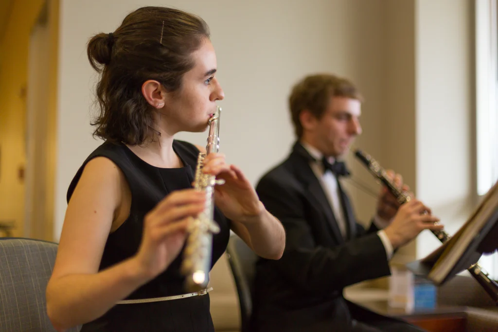A woman playing the flute and a man playing the oboe, both dressed formally, perform music indoors with passion—a delightful scene that could inspire any Valpo Engineering Student to appreciate the art of music.