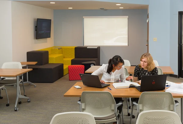 Two women collaborate at a table with laptops in the modern, brightly lit Innovation Hub at Valparaiso University.