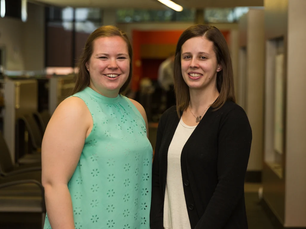 Two women, including faculty member Jennifer Marley, smile together in an indoor office or library at the College of Engineering.