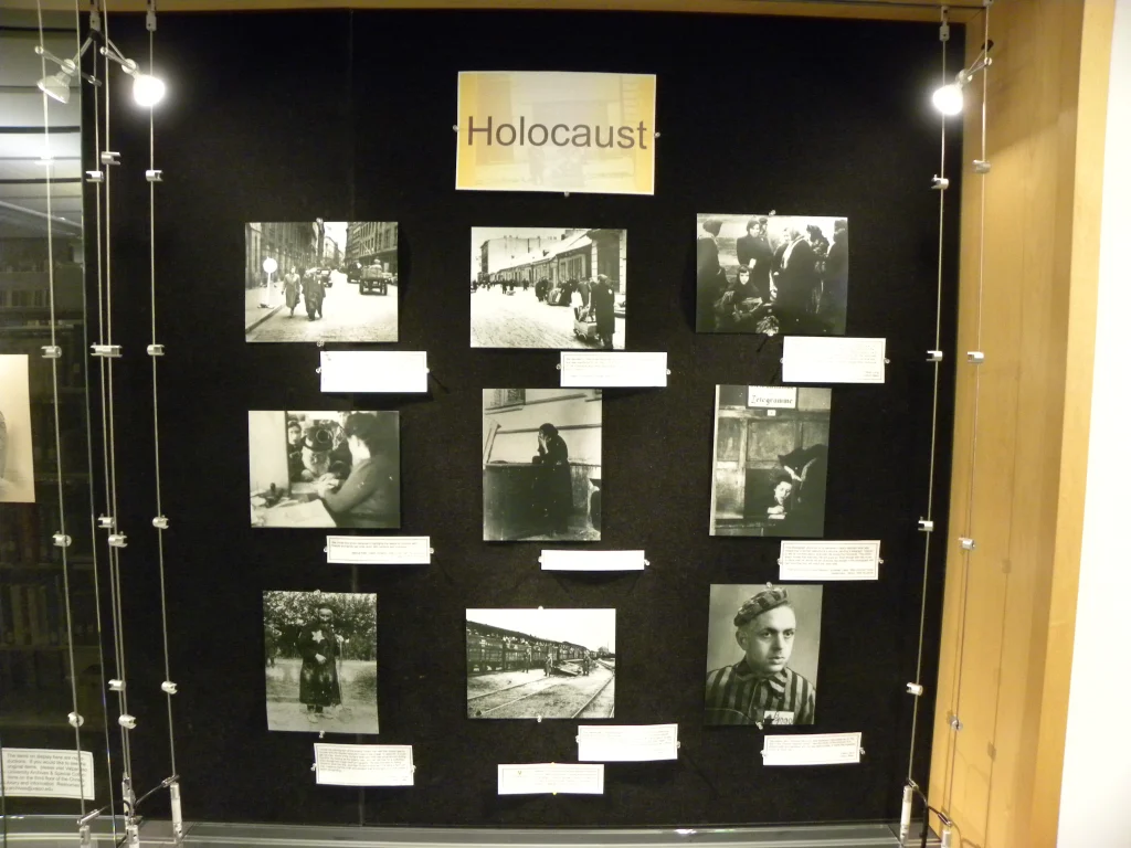 A display board labeled "Holocaust" featuring historical black-and-white photos and captions, part of the Holocaust Displays at the Christopher Center.