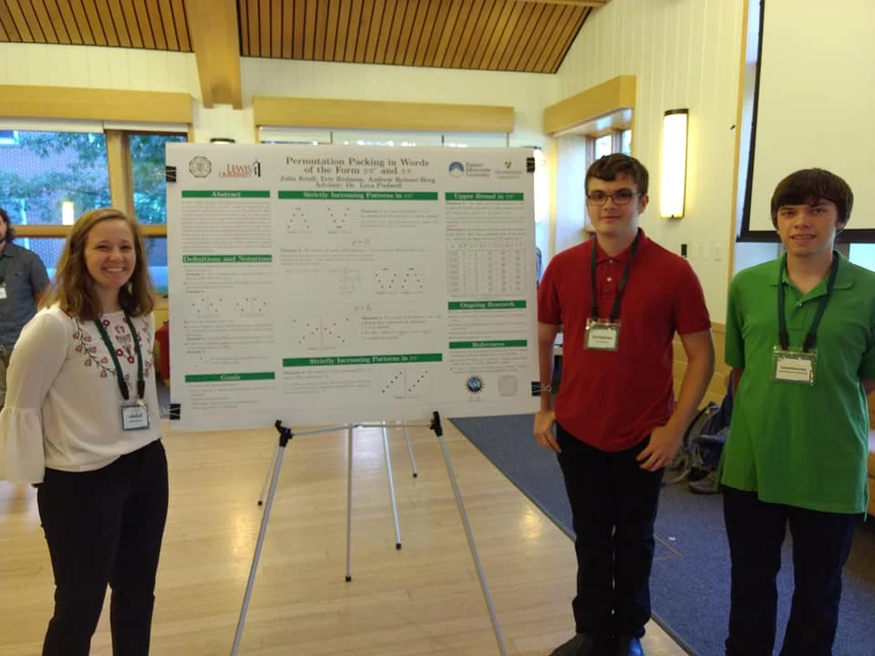 Three students stand by a scientific poster on Permutation Patterns at an indoor presentation event, representing Valpo at an International Conference.