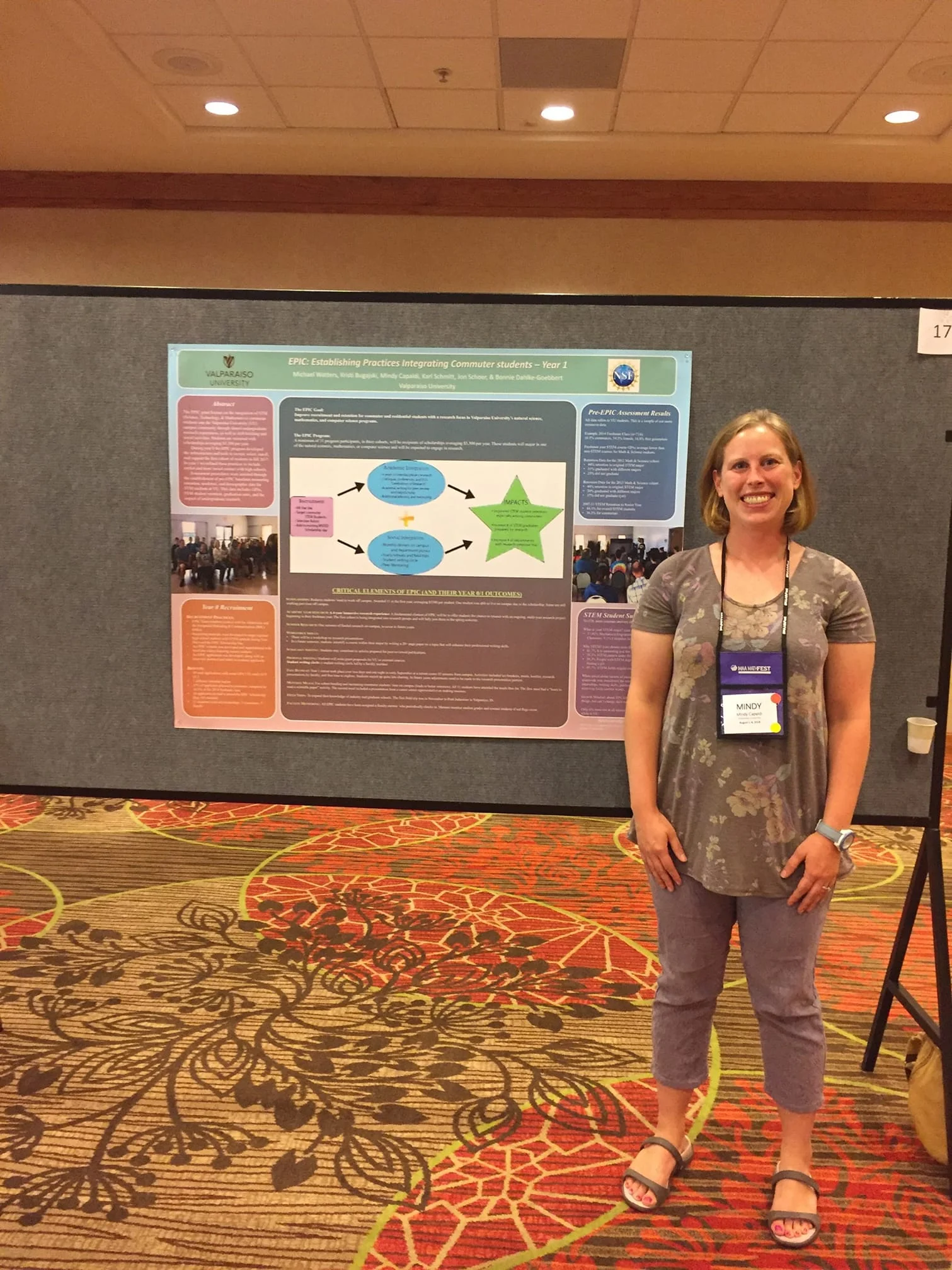 Woman standing and smiling in front of a large scientific poster at Mathfest 2018, representing Valpo MST faculty at the conference.