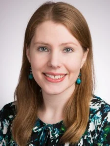 Woman with long light brown hair, wearing teal earrings and a patterned top, smiling at the camera—her warmth reflects her commitment to Excellence in Teaching at Kolba.