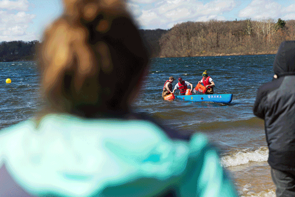 Engineering students paddle a canoe on the lake, as two people in jackets—likely Valpo Engineering peers—watch from the shore, perhaps during a regional conference gathering.