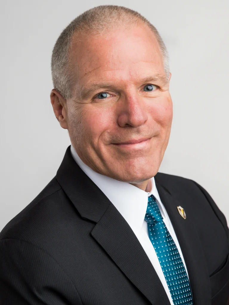 Smiling man in a suit and tie with short gray hair, looking confident against a plain light background—perfect for depicting a university president at Valparaiso University.