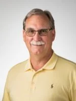 Smiling older man with glasses, gray hair, and a mustache, wearing a light yellow polo shirt—a distinguished Valpo Faculty Member.