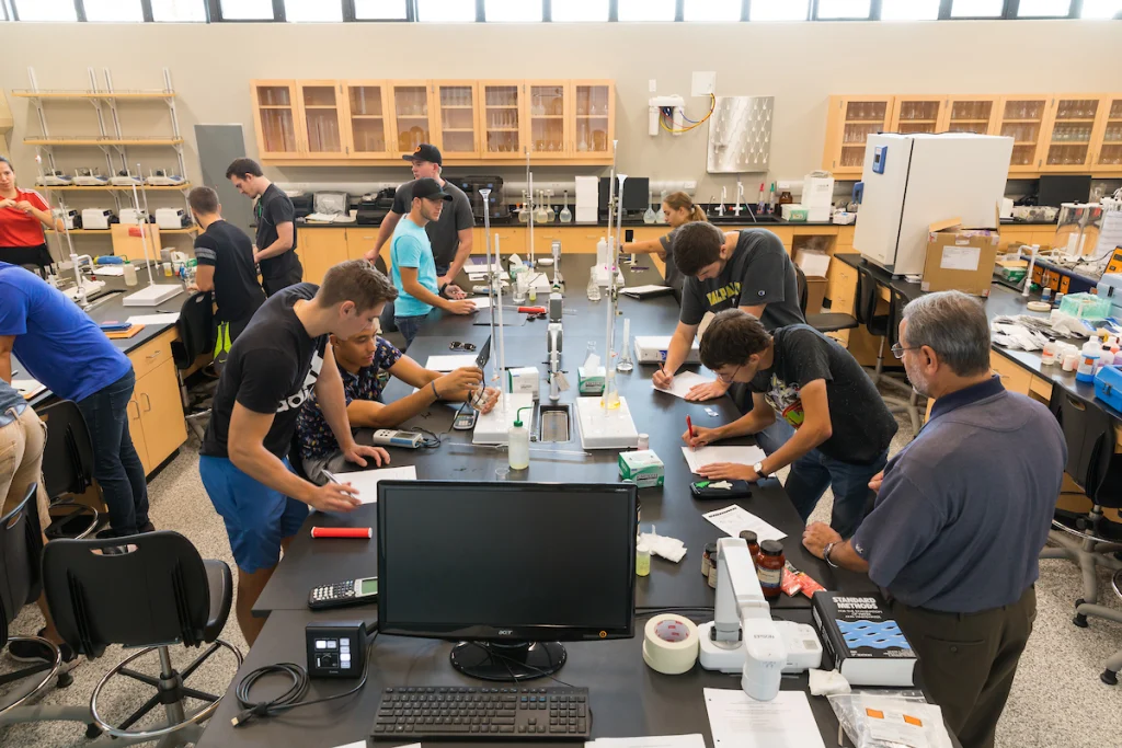 Students collaborate on experiments and take notes in a busy Environmental Engineering Lab, demonstrating lab dedication and teamwork.