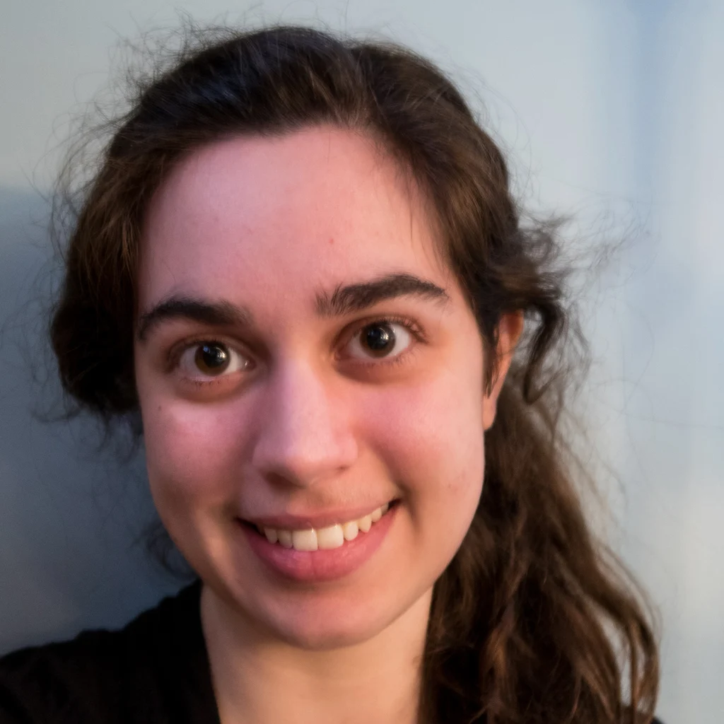 A young woman with long brown hair, a proud member of the 2020 Class, smiles at the camera against a plain light background.