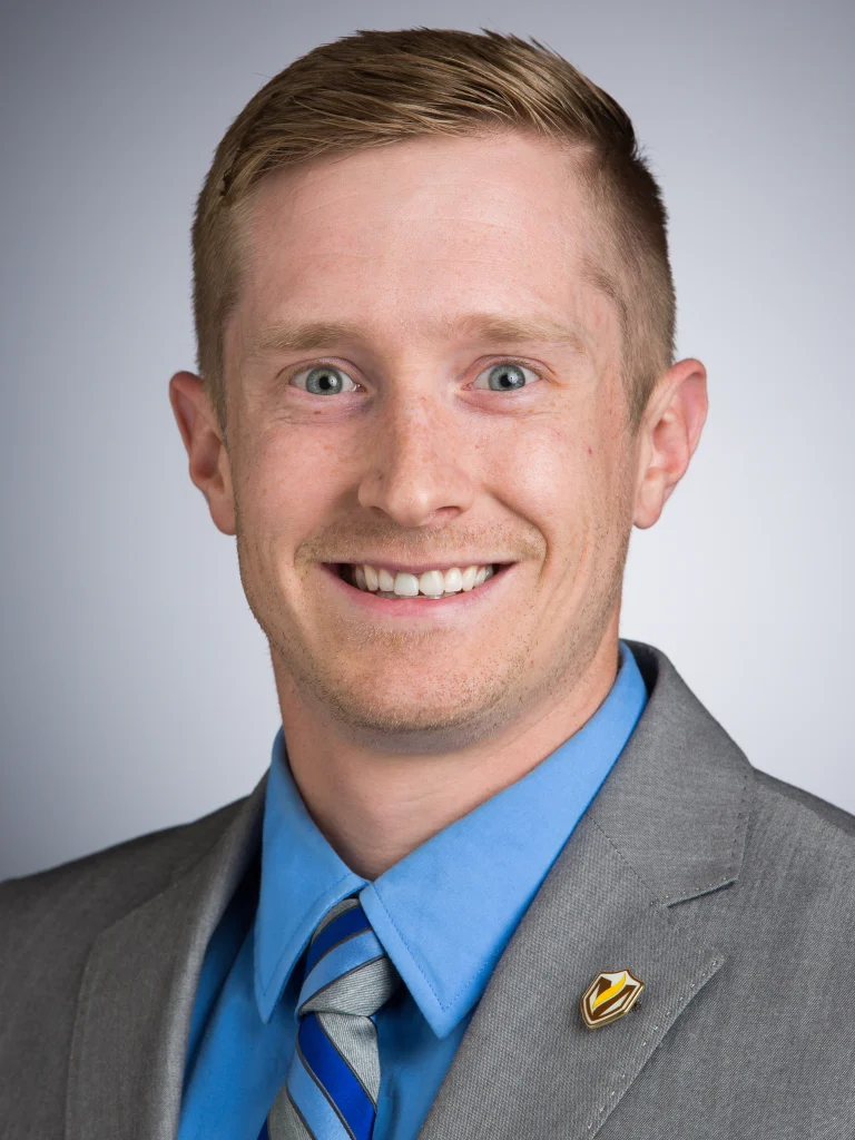 Smiling man in a gray suit, blue shirt, and striped tie, posing for a professional headshot—ideal for roles in emergency management or Incident Command Team leadership.