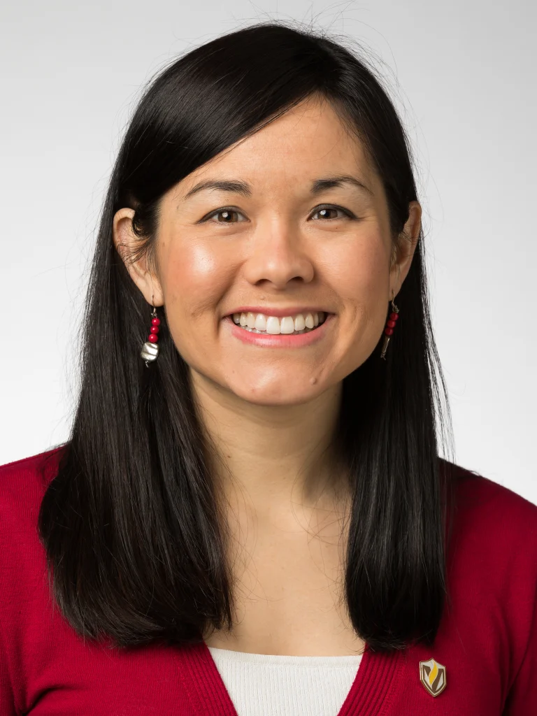 Smiling woman with straight black hair, wearing a red sweater, red earrings, and a pin on her collar—one of the distinguished Valpo Professors recognized for University Research Professorships.