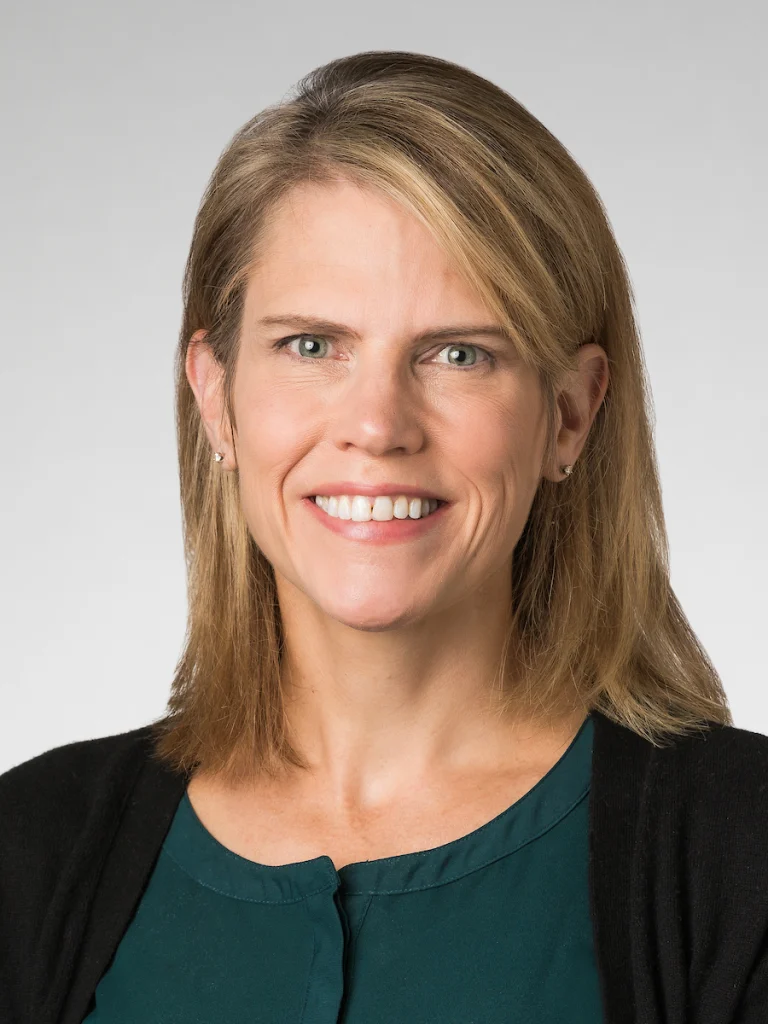 Smiling woman with straight blonde hair, wearing a green top and black cardigan, and proud Award Recipient of the Kapfer Research Award at Valparaiso University, stands against a light background.