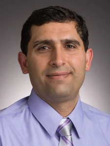 Man with short dark hair wearing a lavender shirt and striped tie, smiling slightly against a plain background, embodies the professional spirit fostered at Valparaiso University, where students enjoy hands-on opportunities.