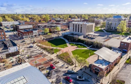 Aerial view of a small city square with green spaces, brick buildings, and light traffic on a sunny day—explore the best restaurants Valpo has to offer in this charming setting.