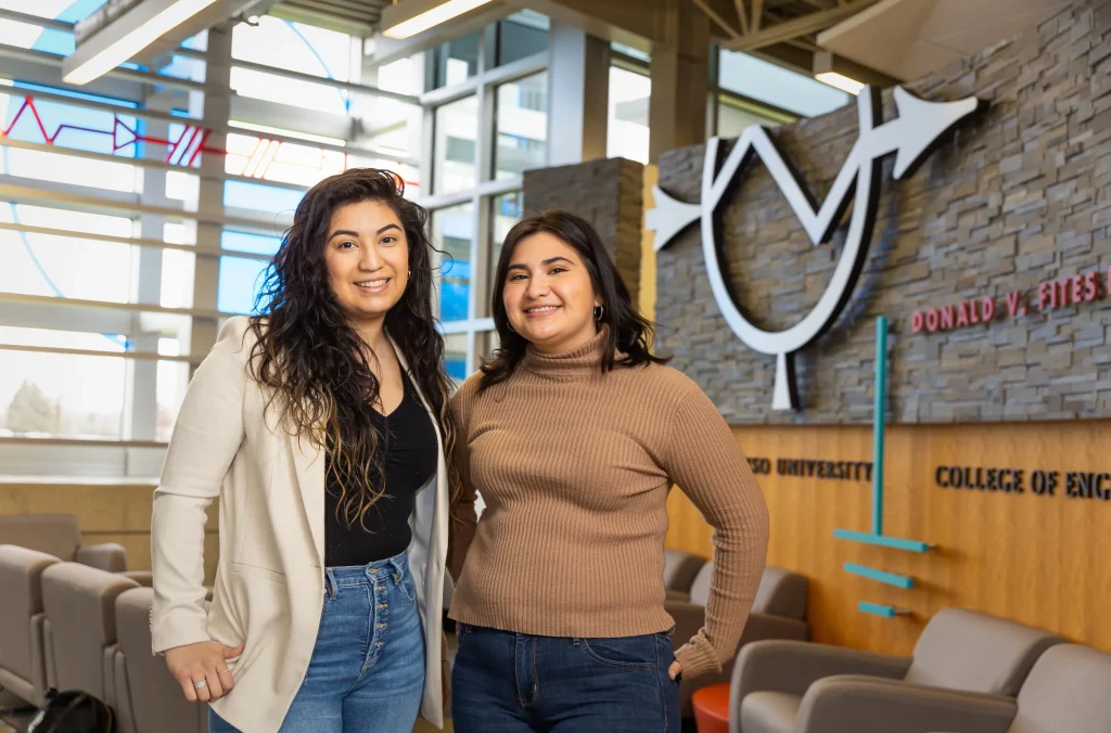 Two women smiling and standing in a modern campus lounge at Valparaiso University, reflecting its welcoming and inclusive community.