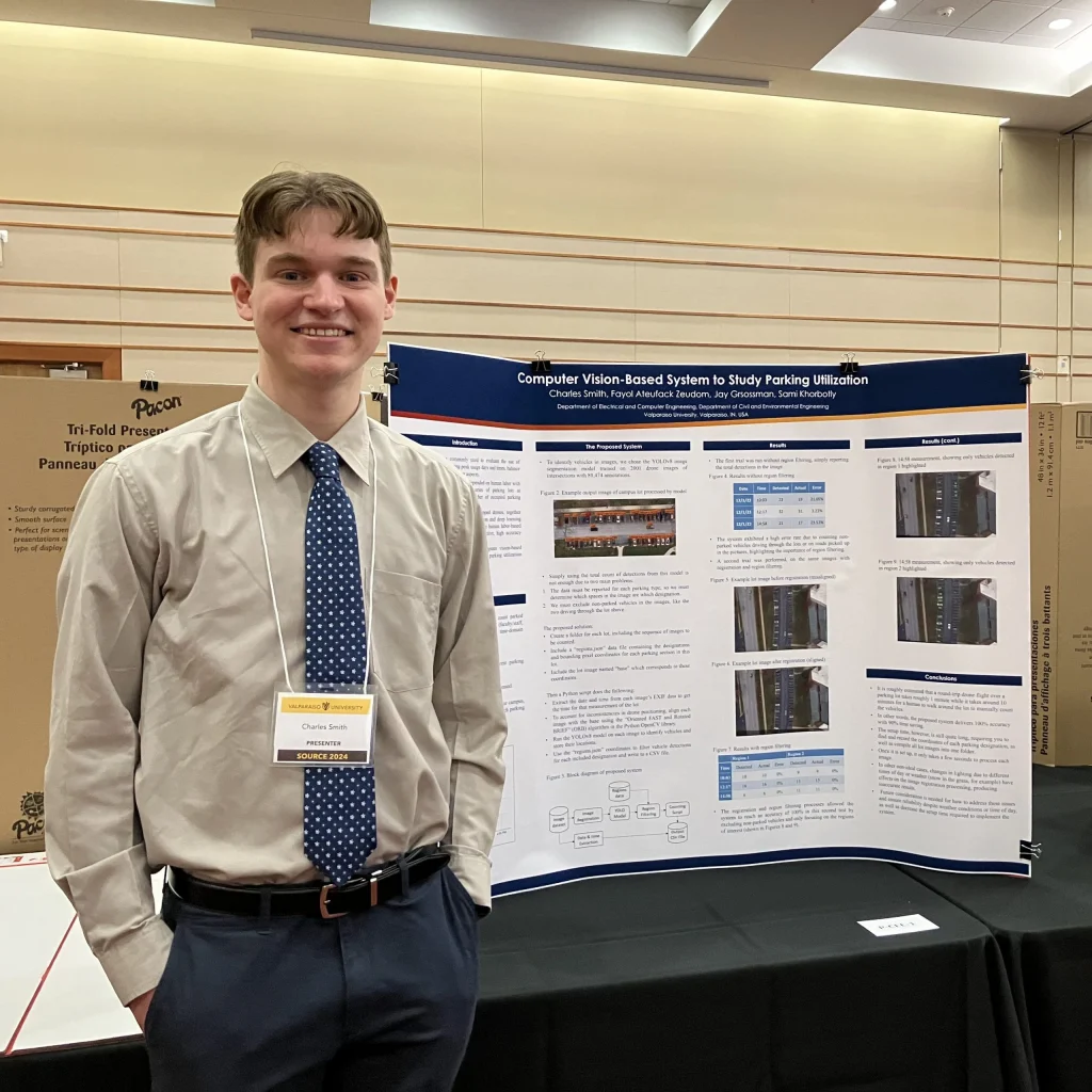 Young man in business attire stands by a science fair poster about computer vision and parking utilization, showcasing innovation inspired by Fayol Ateufack Zeudom.