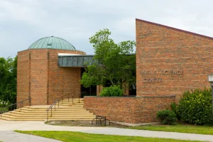 Brick building with dome roof, entrance steps, and sign reading "Neils Science Center" on the wall.