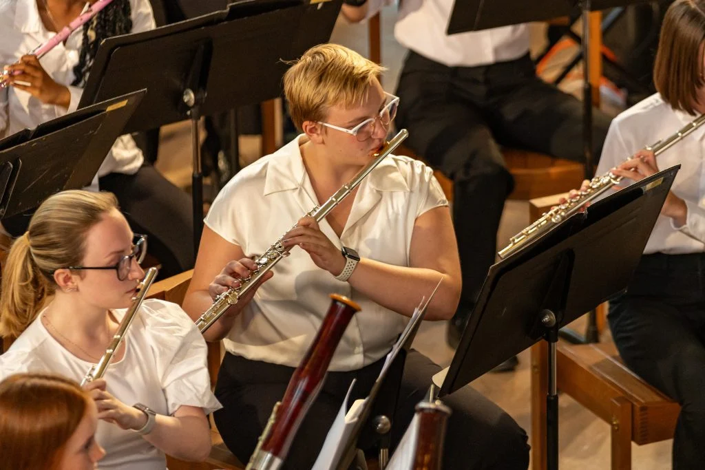 Orchestra members in white shirts play flutes and other woodwinds during a Summer Music performance, celebrating the rich liturgical legacy of Lutheran Summer Music.
