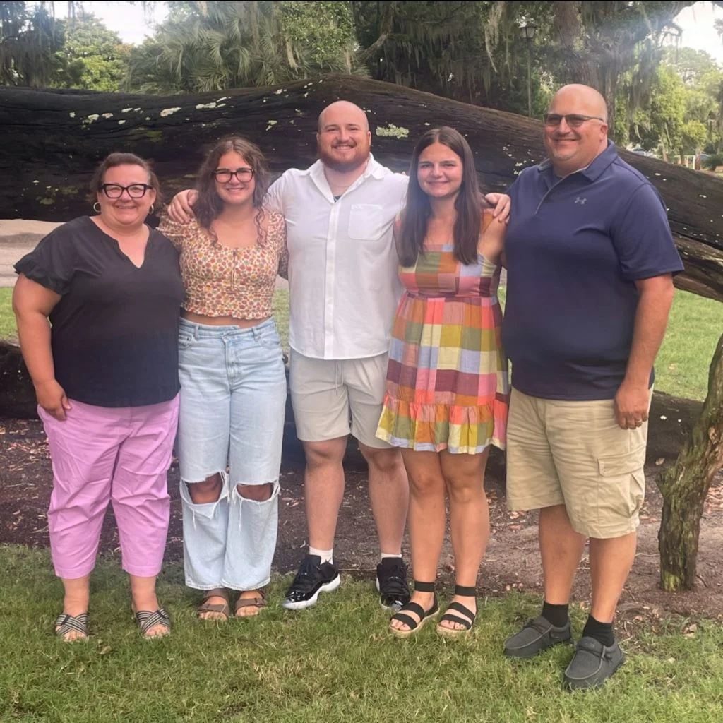 Five people, including Tyler Eberhart, stand smiling together outside in front of a fallen tree, posing for a group photo that reflects the spirit of Valpo Football and servant-leadership.