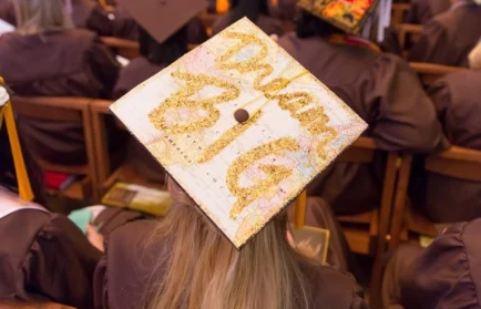A graduate from Valparaiso University wears a cap decorated with the words "Dream Big," symbolizing excellence at the graduation ceremony.