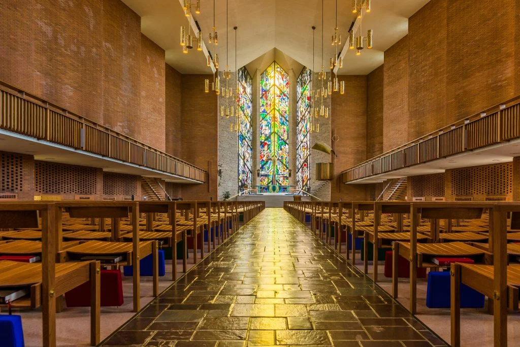 A church interior with wooden pews and colorful stained glass windows at the front, this Haven of Hope offers a peaceful sanctuary for quiet reflection.