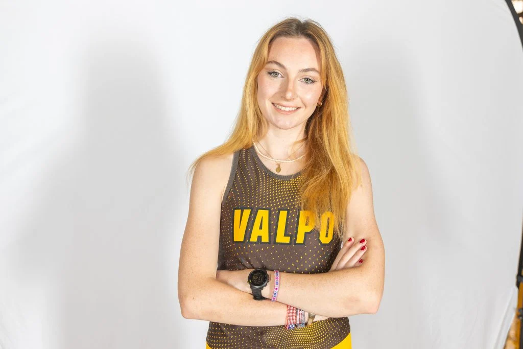 Laëtitia Raoult, in a Valpo athletic uniform, stands with arms crossed and a warm smile, celebrating her 4,000-mile journey in front of a plain white background.