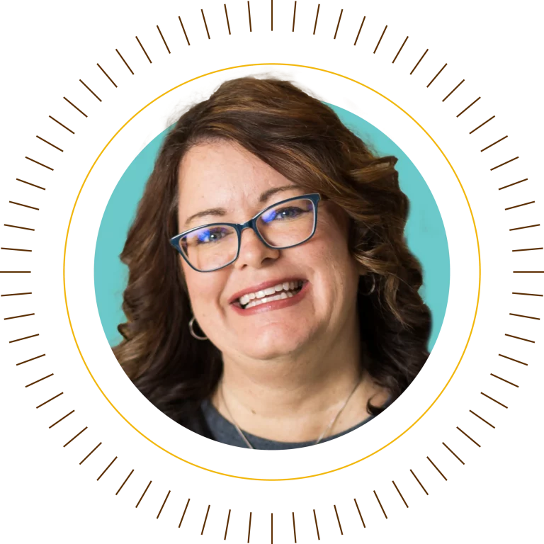 Woman with shoulder-length brown hair, glasses, and a warm smile shines in front of a teal background—representing Valpo with confidence.