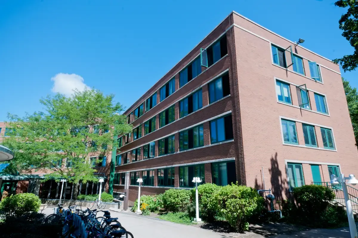 Wehrenberg Hall is a four-story brick building with many windows, surrounded by trees and bushes under a clear blue sky.