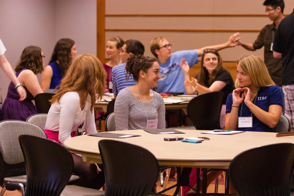 People sitting in groups at round tables, talking and interacting in a casual indoor setting, discuss updates to the Valparaiso University Travel Policy.