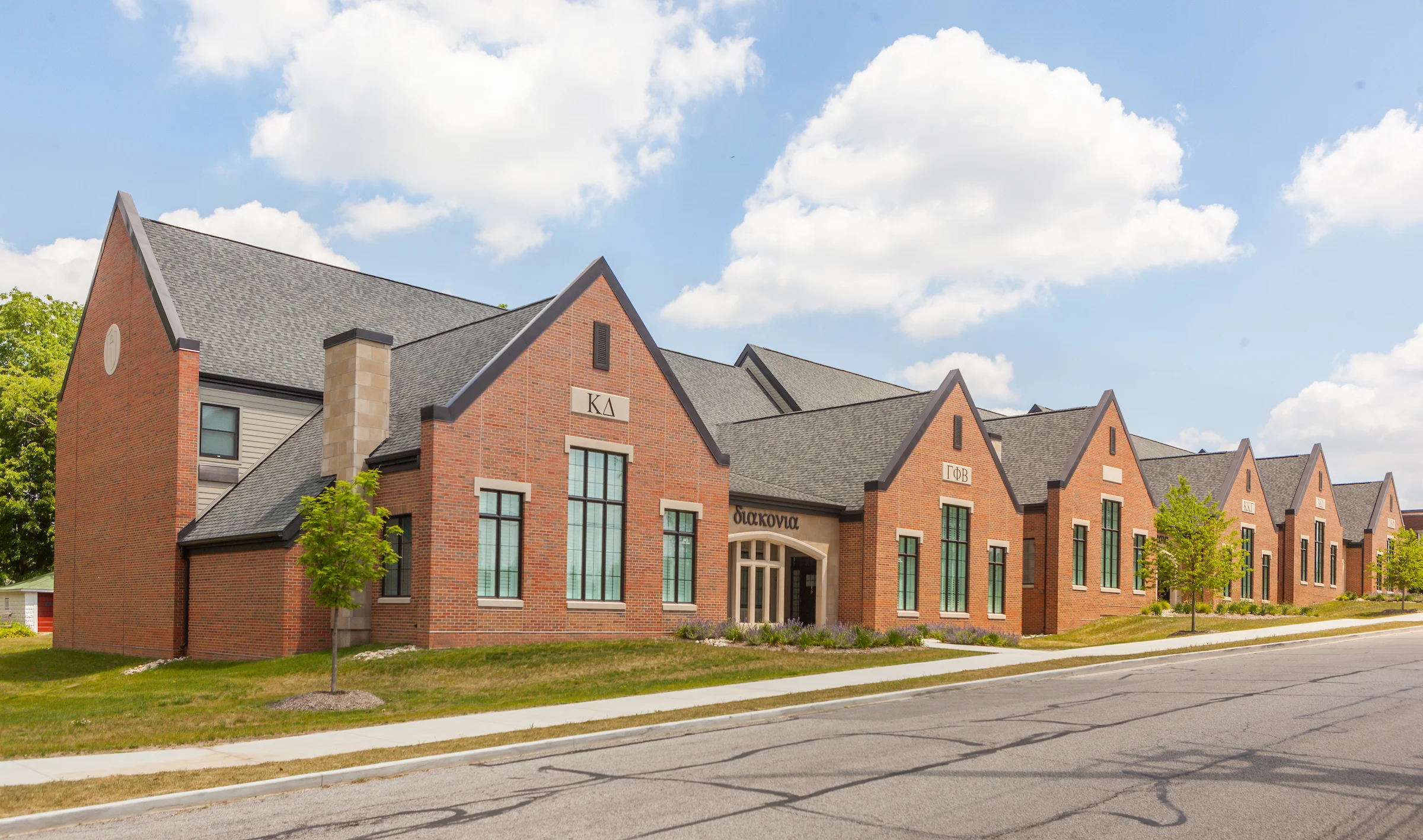 Red brick school building with peaked roofs, large windows, and a sign reading "Oxford" above the entrance. Information for New Students is available upon entry.