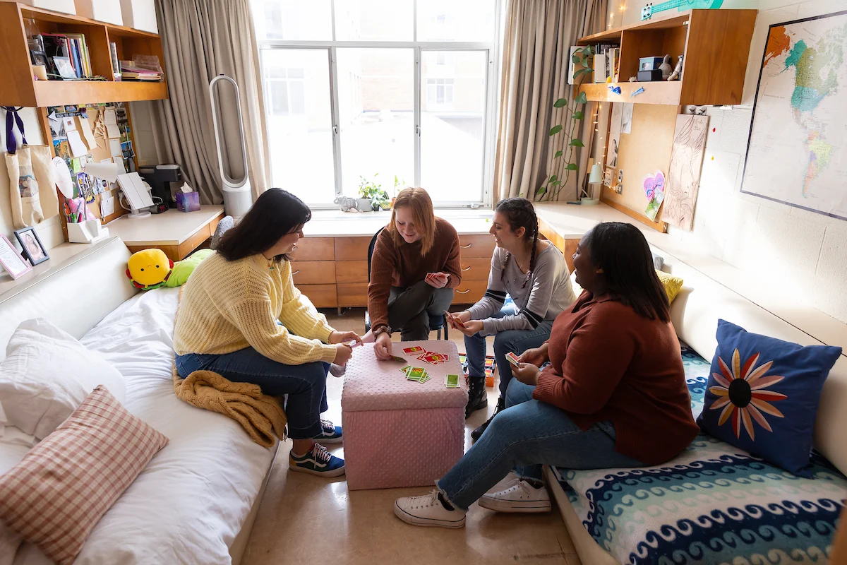Four admitted students sit in a dorm room together