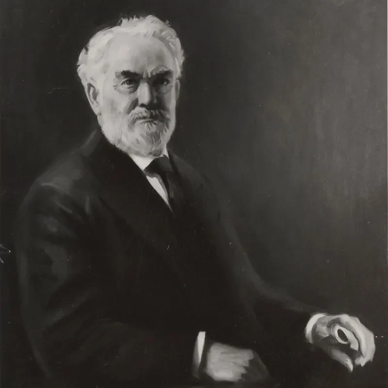 Black and white portrait of an older man with a beard, wearing a suit, seated and looking at the viewer—an image reflecting wisdom, leadership, and governance.