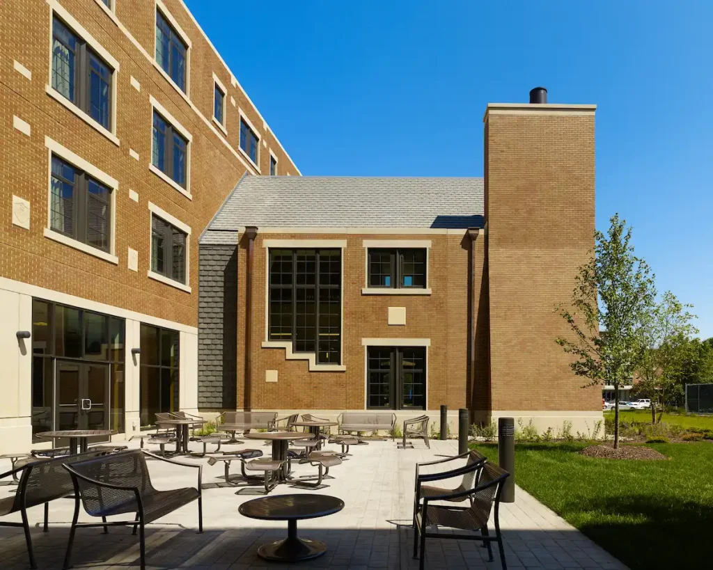 Outdoor patio with tables and chairs beside a brick building under a clear blue sky.
