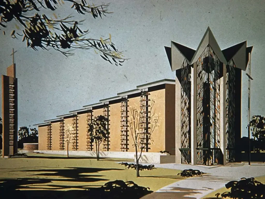 Modern church building with tall stained-glass windows and angular roof, surrounded by trees and grass—an inspiring setting for commencement ceremonies.