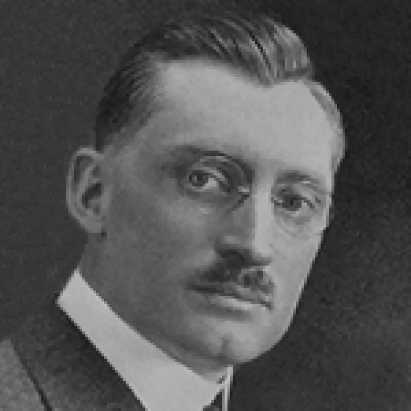 Black and white portrait of a man with glasses, a mustache, and neatly combed hair, wearing a suit—a classic representation of leadership & governance.