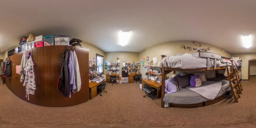 A cozy dorm room in a Sorority Housing Complex features bunk beds, desks, shelves, and walls decorated with photos and string lights.