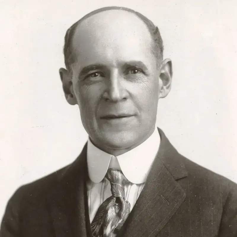 A man in a suit and tie poses for a formal black-and-white portrait photo, reflecting professionalism and the essence of leadership & governance.