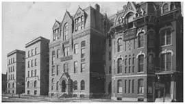 Historic black-and-white photo of large brick buildings with arched windows and ornate architectural details.