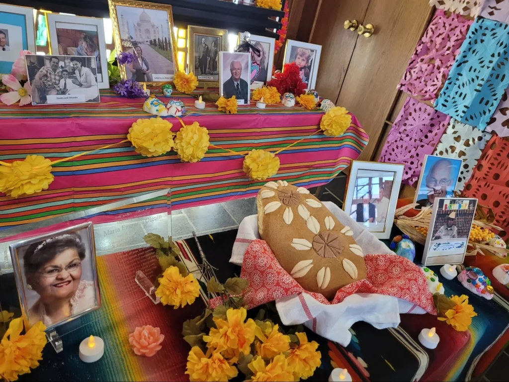 An ofrenda decorated with photos, marigolds, candles, and pan de muerto for Día de los Muertos in the heart of Vale.