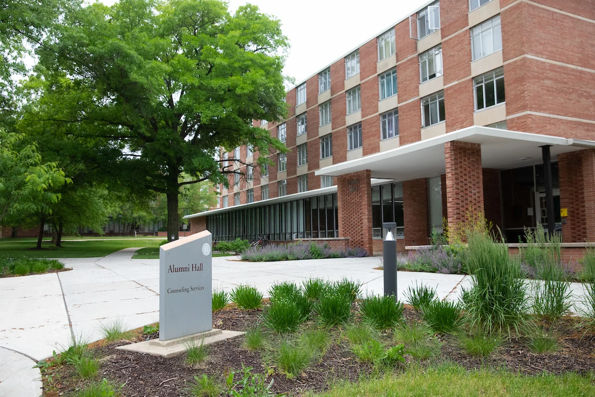 A brick building labeled Alumni Hall features a sign for Counseling Services and well-maintained landscaping in front.