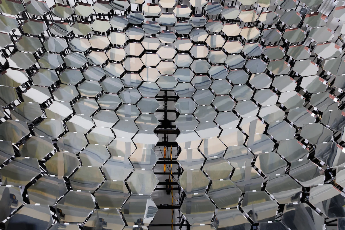Close-up of a shiny, hexagonal, mirrored surface on campus reflecting light and surroundings in a honeycomb pattern.
