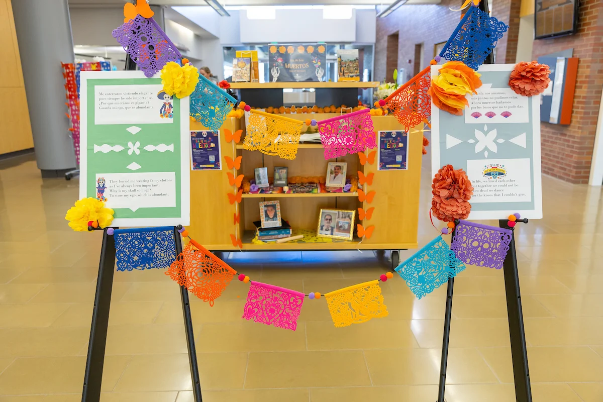 Colorful papel picado and flowers decorate the Vale library display, featuring books and informational posters.