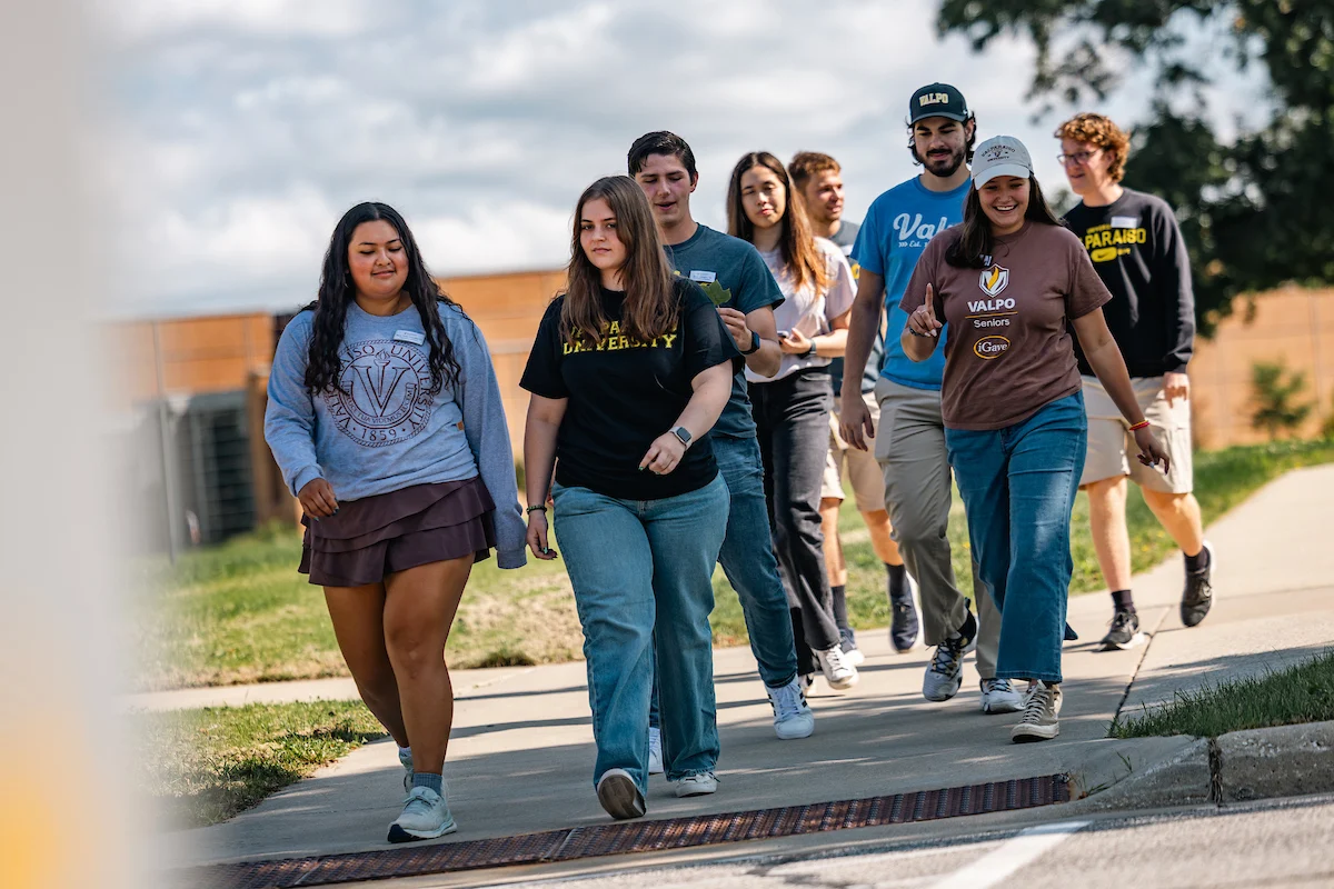 A group of college students walk together on a campus sidewalk during Admitted Student Tours on a sunny day.