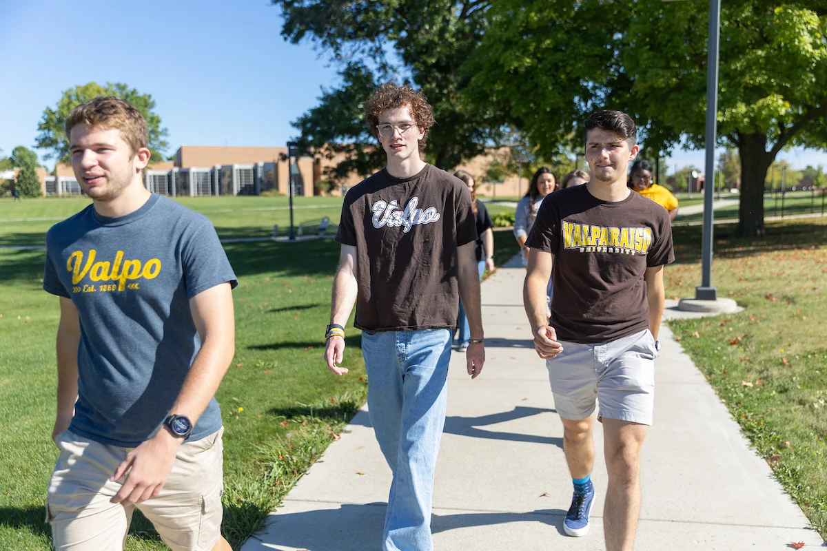 Three college students walk outside on a sunny day, wearing Valparaiso University T-shirts after stopping by the Registrar’s office.