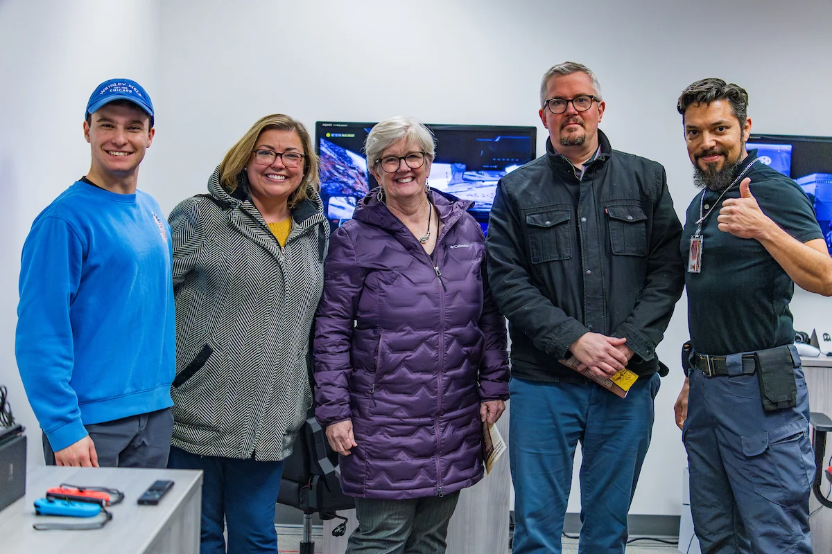 Five people, including a registrar, stand indoors, smiling at the camera; one person gives a thumbs-up gesture.